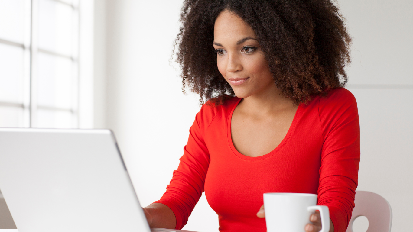 image shows a woman using a laptop searching for the right domain name to buy for her business